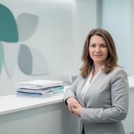 Dental clinic director standing beside a reception counter and compliance folders